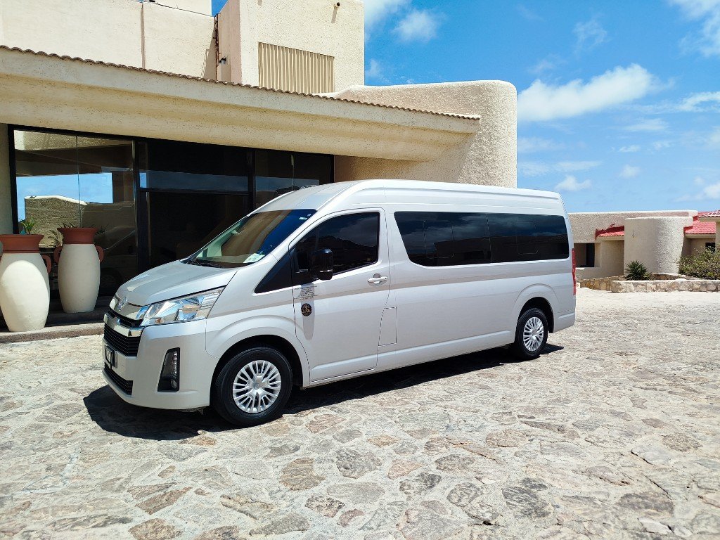 Toyota Hiace plateada de Torote Luxury Transportation estacionada frente a un edificio.