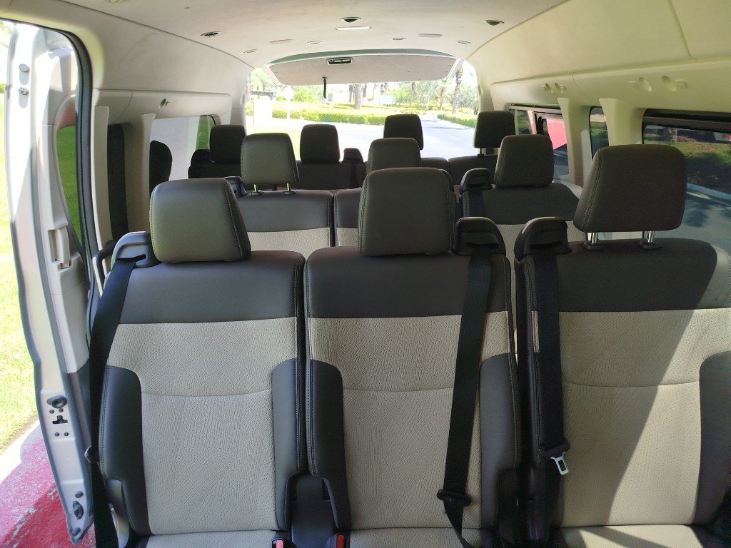 Interior del Toyota Hiace con filas de asientos amplios y cinturones de seguridad.